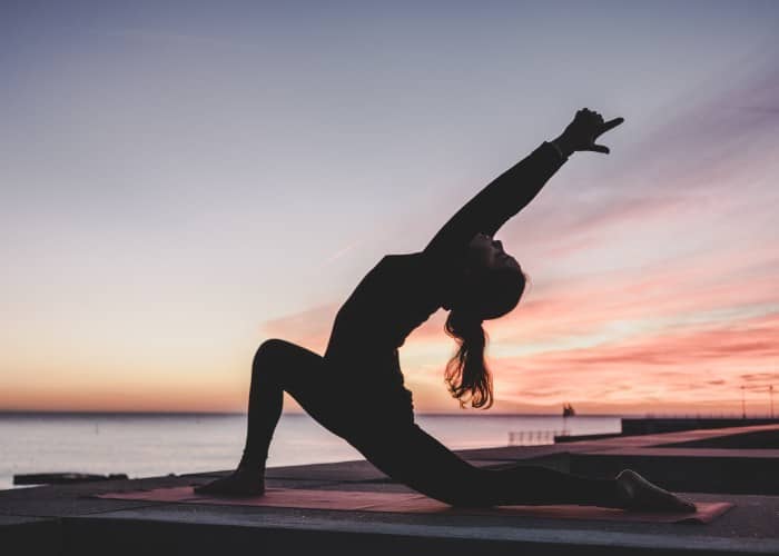 a person practicing yoga on a beach at sunset